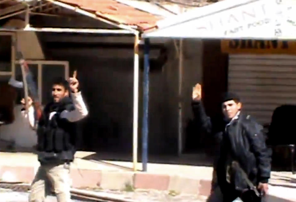 This Sunday, March 23, 2014 image taken from video obtained by the anti-government activist group Shaam News Network, which has been authenticated based on its contents and other AP reporting, shows Syrian fighters holding their weapons as they gesture after seizing the predominantly Armenian Christian town of Kassab, Syria. The rebels, including militants from the al-Qaida-affiliated Nusra Front, have also wrested control of a nearby border crossing to Turkey (AP Photo/Shaam News Network via AP video)