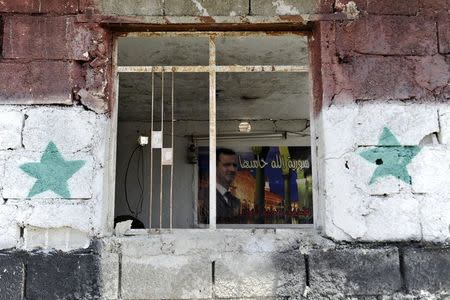 A picture of Syria's President Bashar al-Assad is seen inside a checkpoint at the site of a car bomb on the outskirts of the Sayeda Zeinab district south of Damascus, Syria, April 25, 2016. REUTERS/Omar Sanadiki TPX IMAGES OF THE DAY