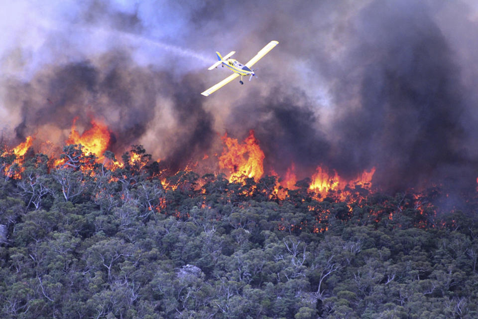 In this Thursday, Jan. 16, 2014 photo released by Victoria Country Fire Authority, a water bomber works over a large fire burning throughout Victoria's Grampians region. Fire authorities in Victoria said there are 68 fires burning at present with stronger winds expected Friday afternoon, urging residents in these affected regions to evacuate. (AP Photo/Country Fire Authority)