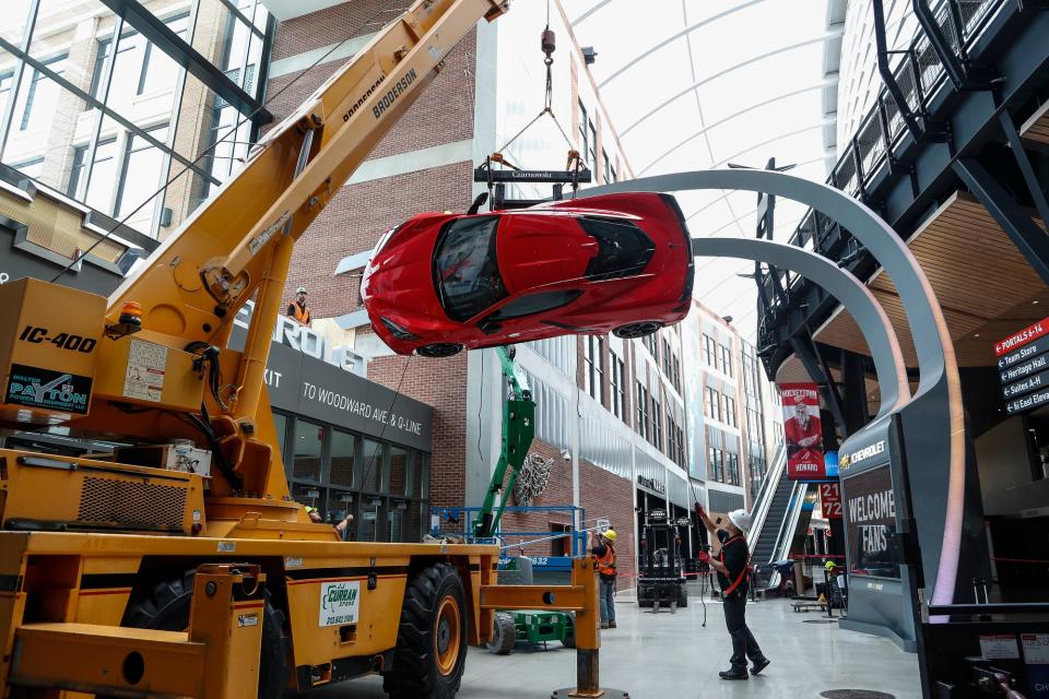 Workers install the 2020 Corvette Stingray on the wall at the northeast entrance of the Little Caesars Arena in downtown Detroit, Tuesday, September 10, 2019.