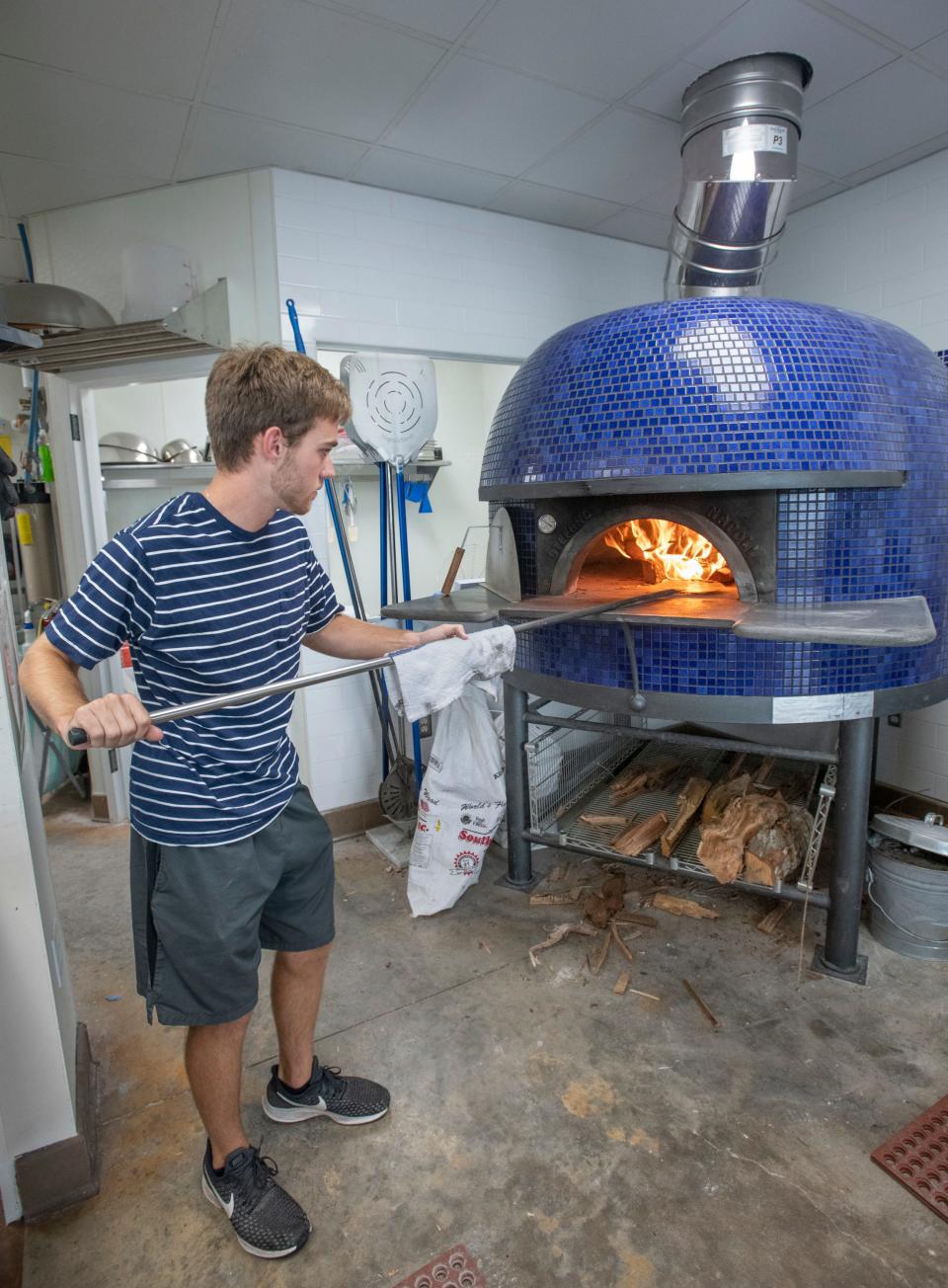 Colby Fenters stokes the fire in the brick oven at Pizzaluté Woodfired Pizza & Tap Bar in Perdido Key on Wednesday, August 26, 2020.