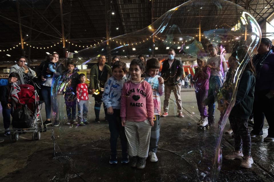 Children pose for a photo inside a giant soap bubble during spring holidays, in Montevideo, Uruguay, on Sept. 23, 2022. (AP Photo/Matilde Campodonico)