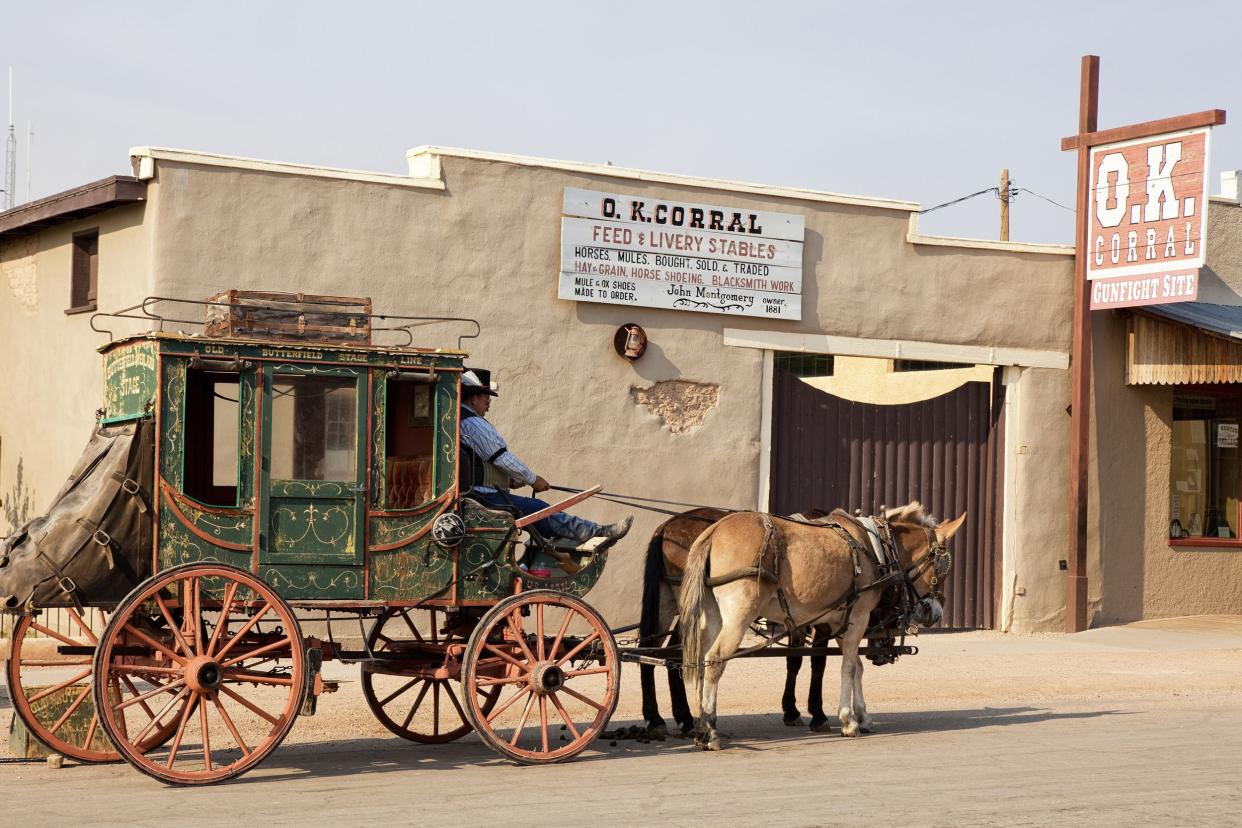Stagecoach with two horses in front of the O.K. Corral on Allen Street in Tombstone, Arizona, blue-grey sky in the background