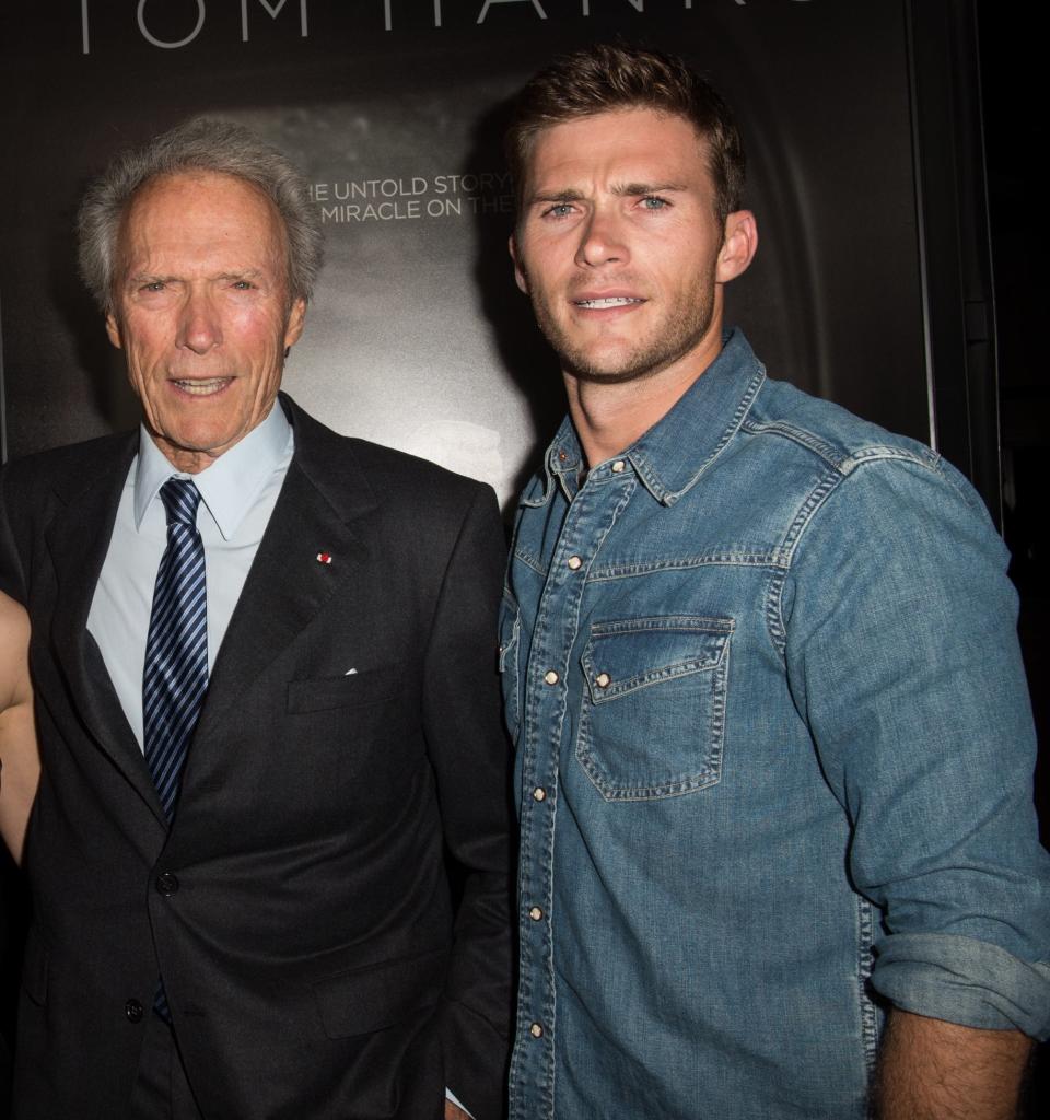 father and son  pose at a premiere; Clint in a suit flanked by Scott in denim