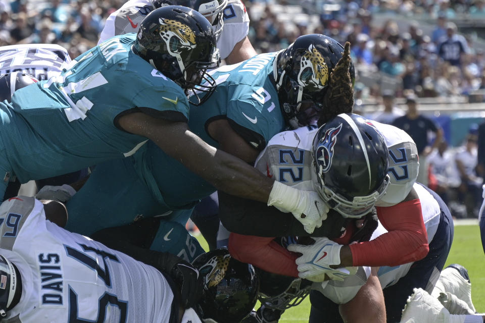 Tennessee Titans running back Derrick Henry (22) dives past Jacksonville Jaguars outside linebacker Myles Jack, left, and defensive end Dawuane Smoot (91) for a 1-yard touchdown run during the first half of an NFL football game, Sunday, Oct. 10, 2021, in Jacksonville, Fla. (AP Photo/Phelan M. Ebenhack)