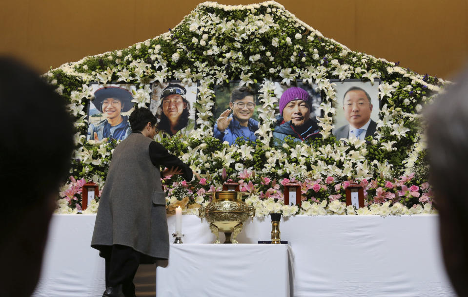 A mourner places a flower to pay tribute at a memorial altar for late South Korean mountain climbers at a university in Seoul, South Korea, Wednesday, Oct. 17, 2018. Relatives dressed in black funeral suits wept in grief on Wednesday as the bodies of five South Korean mountain climbers arrived home from Nepal where they had died in a storm last week. (AP Photo/Ahn Young-joon)