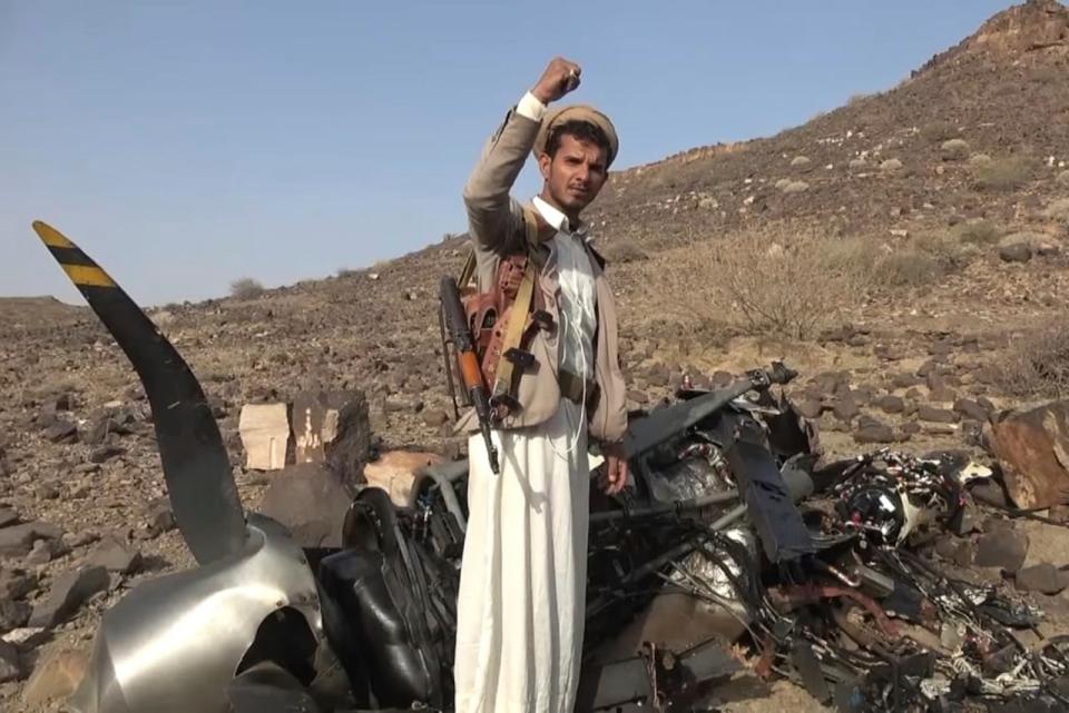 In this photo provided by Houthi media office Saturday, April, 27, 2024, a Houthi fighter celebrates in front of what they said debris of an American MQ9 aerial vehicle, shot down by the air defence forces of the Yemeni Armed Forces in Saada, Yemen, Friday, April, 26, 2024.