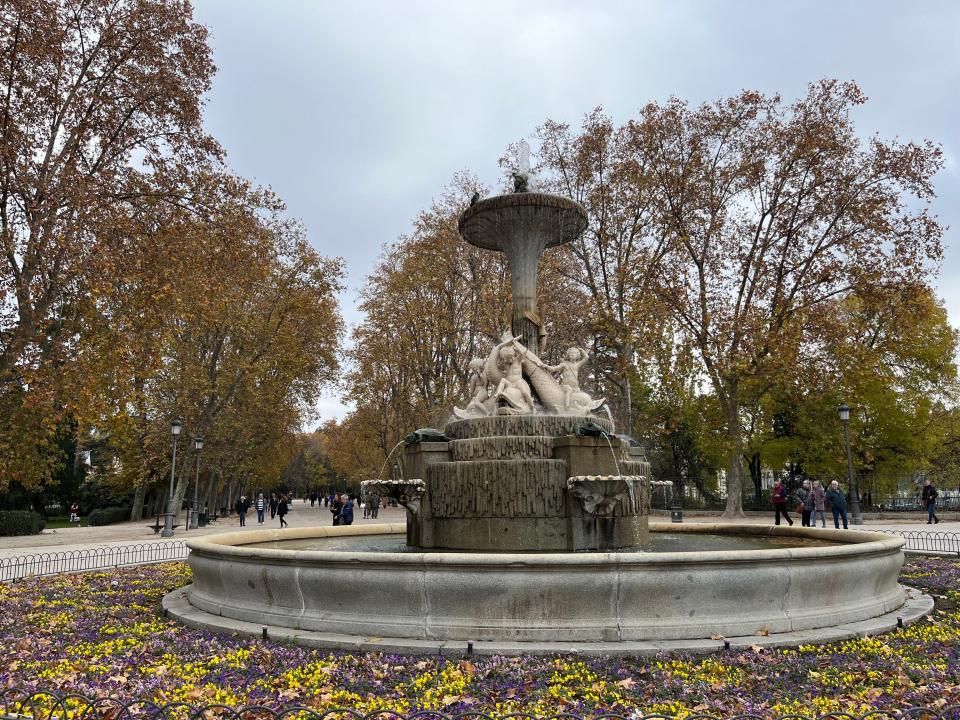 Outdoor stone fountain surrounded by trees.