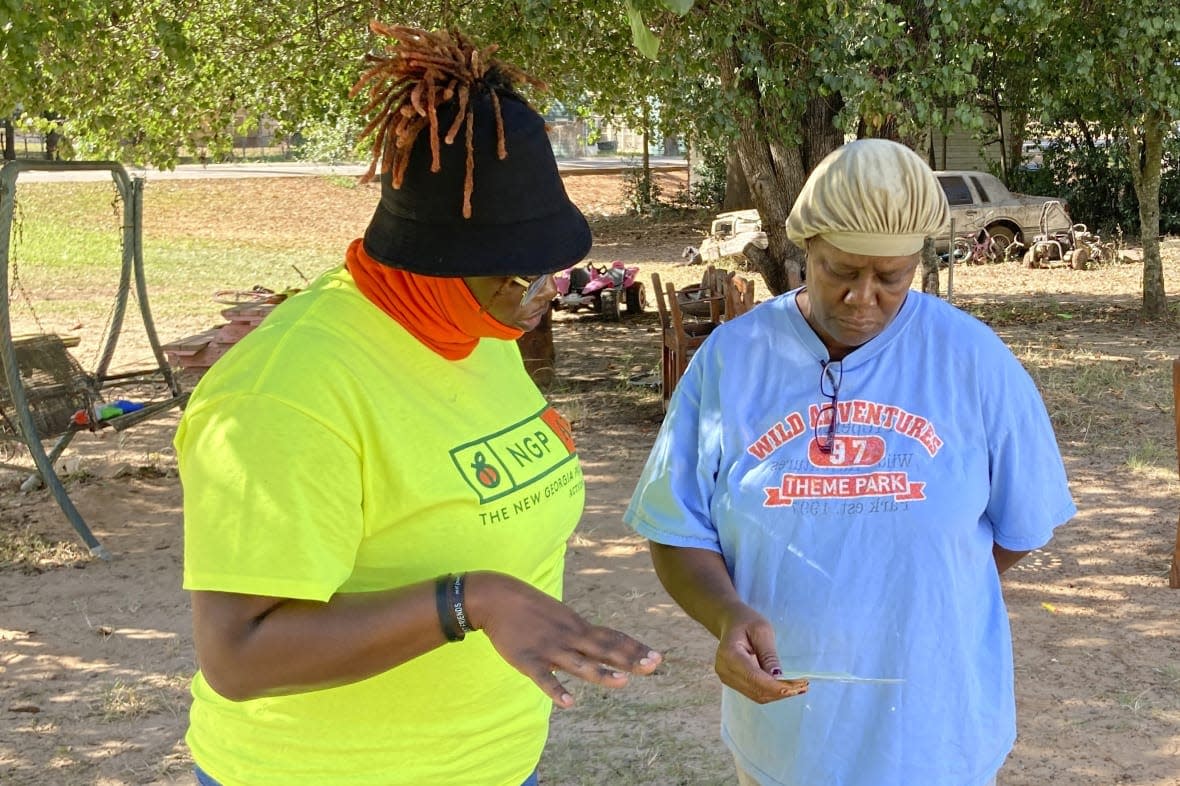 Erika Hardwick, left, a paid canvasser with the New Georgia Project Action Fund, shared literature with Patricia Lee urging Lee to vote on Wednesday, Oct. 5, 2022 in Dawson, Ga. (AP Photo/Jeff Amy)