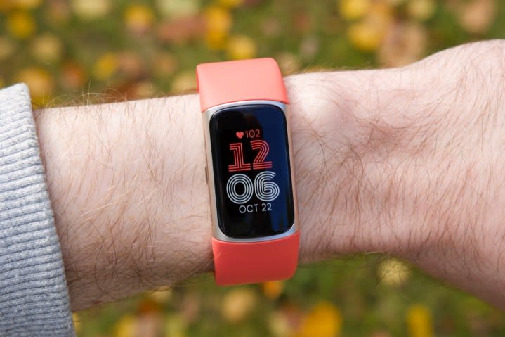 Someone wearing a Fitbit Charge 6 with a coral band.