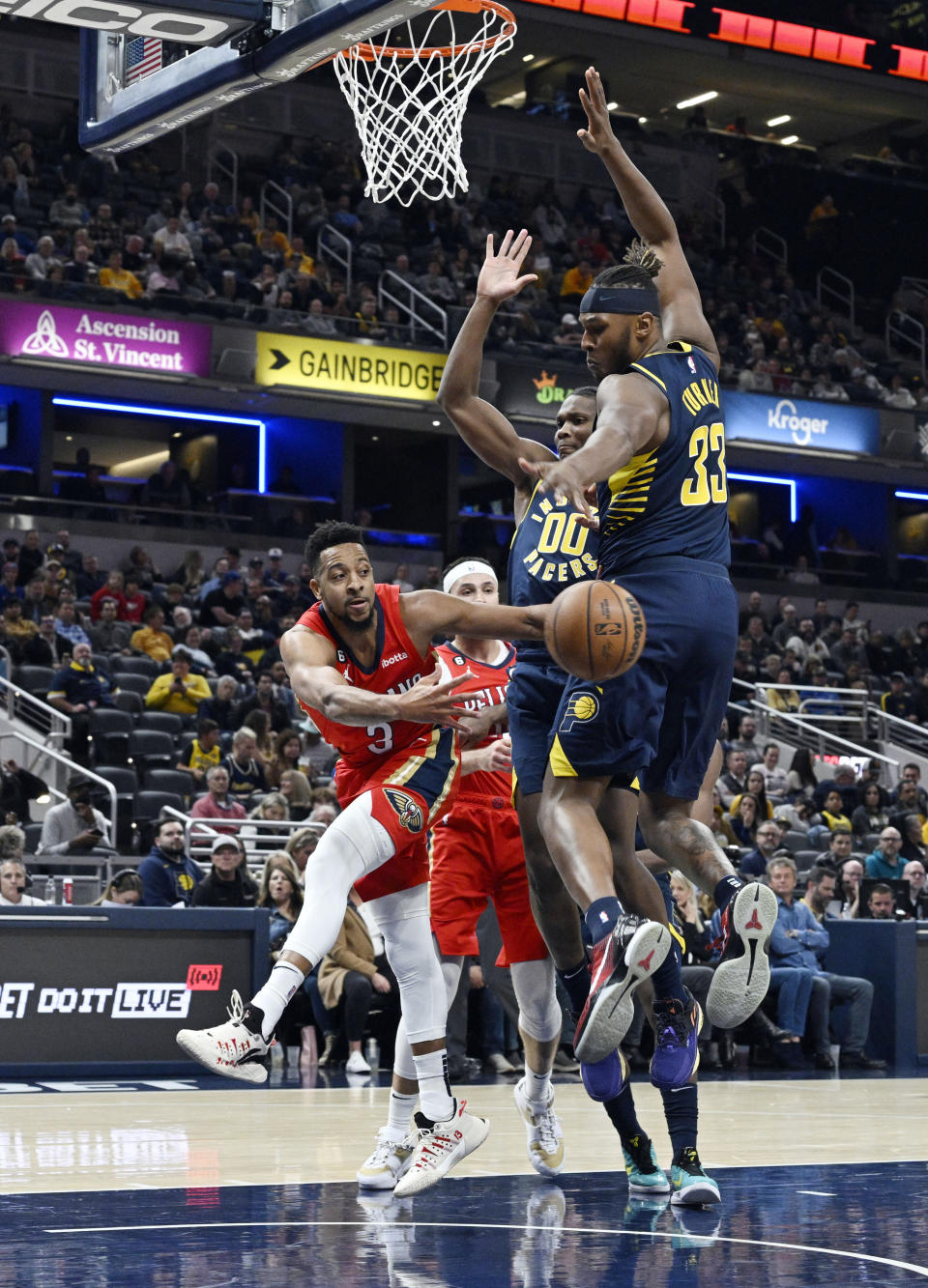 New Orleans Pelicans guard CJ McCollum (3) passes the ball around Indiana Pacers guard Bennedict Mathurin (00) and Indiana Pacers center Myles Turner (33) during the second quarter of an NBA Basketball game, Monday, Nov. 7, 2022, in Indianapolis, Ind. (AP Photo/Marc Lebryk)