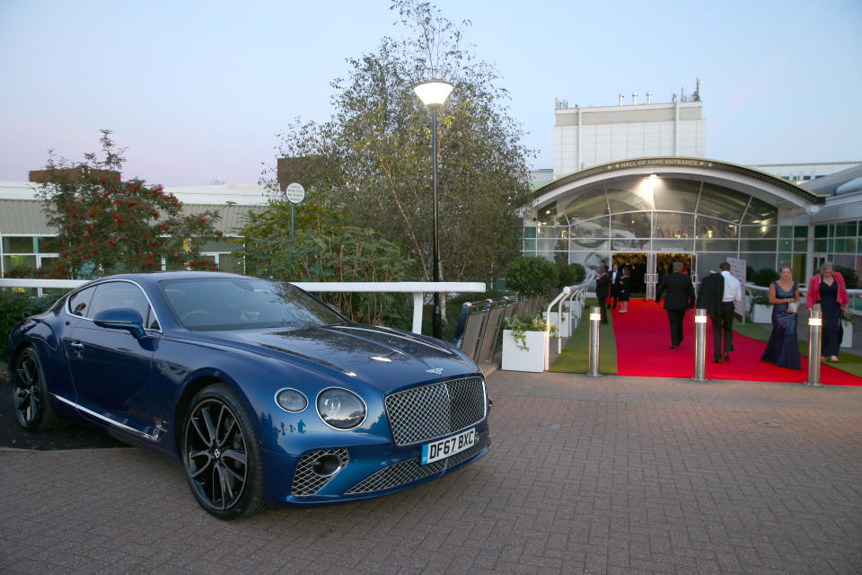 Guests walk past a Bentley car as they arrive at the Jockey Club Awards 