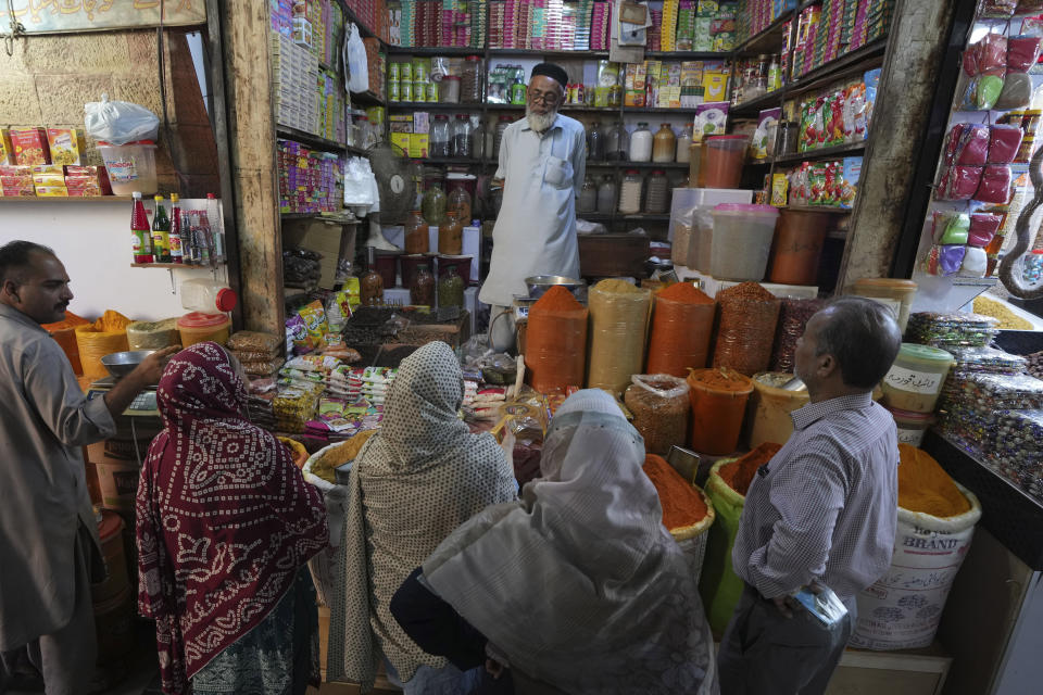 People buy spices from a shop in a market, in Karachi, Pakistan, Tuesday, Feb. 14, 2023. Cash-strapped Pakistan nearly doubled natural gas taxes Tuesday in an effort to comply with a long-stalled financial bailout, raising concerns about the hardship that could be passed on to consumers in the impoverished south Asian country. Pakistan's move came as the country struggles with instability stemming from an economic crisis. (AP Photo/Fareed Khan)