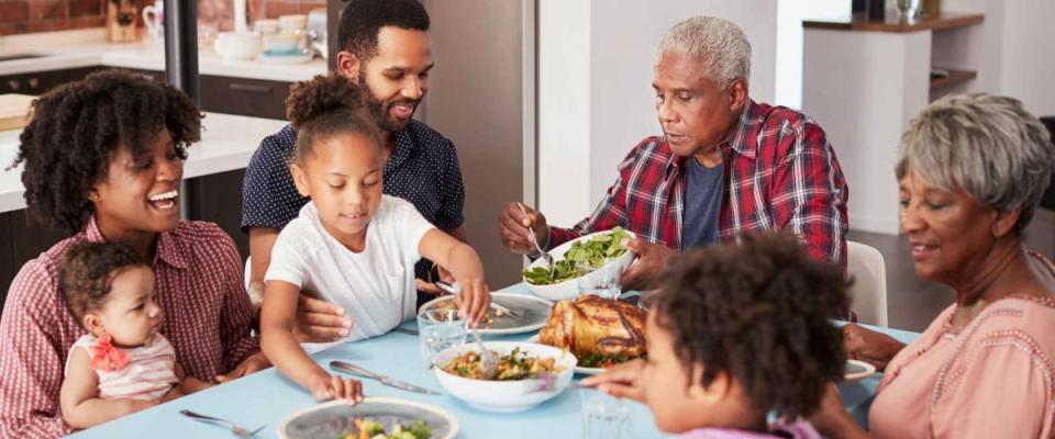 Multi Generation Family Enjoying Meal Around Table At Home