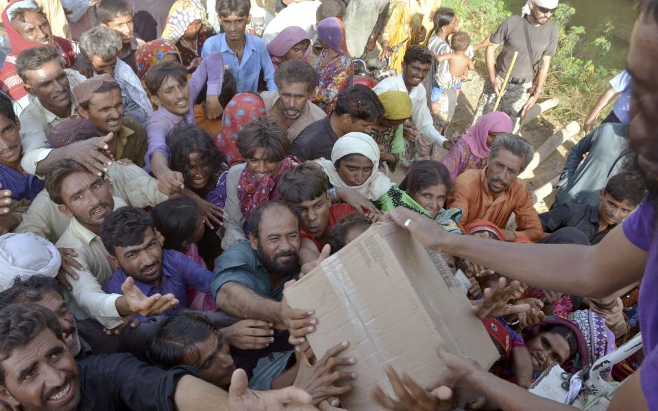 FILE - Displaced families, who fled their flood-hit homes, get relief aid distributed by soldiers of Pakistan rangers, in Dera Allahyar, in Jaffarabad, a district of southwestern Balochistan province, Sept. 17, 2022. A major new United Nations report being released Monday, March 20, 2023, is expected to provide a sobering reminder that time is running out if humanity wants to avoid passing a dangerous global warming threshold. (AP Photo/Zahid Hussain, File)