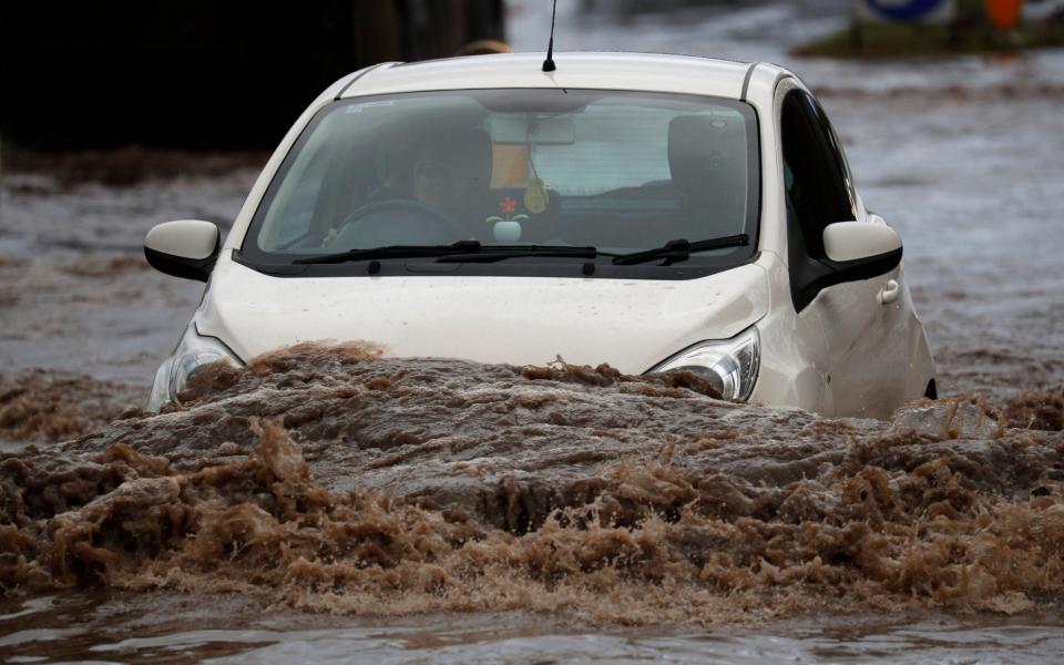  A car is driven through flood water - Darren Staples / Alamy Live News 