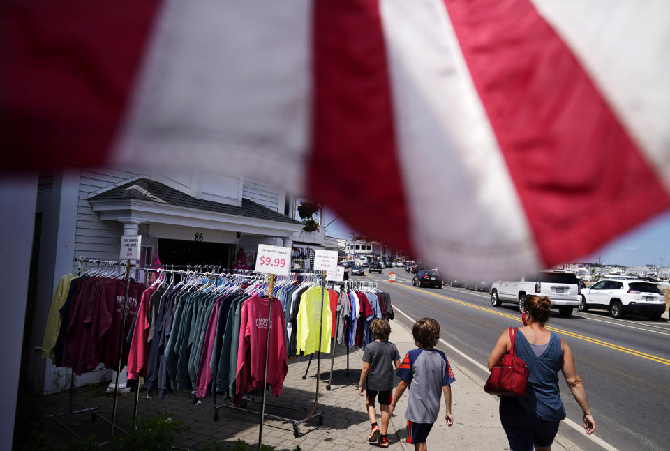 Pedestrians walk past a gift shop in Plymouth, Mass., the traditional point of arrival of the Pilgrims in 1620 on the Mayflower, Wednesday, Aug. 12, 2020. The year 2020 was supposed to be a big one for Pilgrims. Dozens of events, from art exhibits and festivals to lectures and a maritime regatta featuring the Mayflower II, a full-scale replica were planned to mark the 400th anniversary of the religious separatists' arrival at what we now know as Plymouth, Massachusetts. Some historians find it ironic that a pandemic has put many of the 400th anniversary commemorations on hold. (AP Photo/David Goldman)