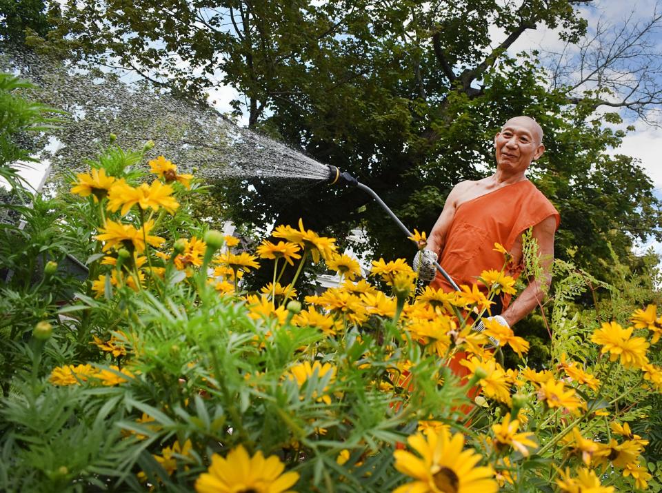 Khmer Buddhist Monk Ka Thann waters the flowers at the Wat Udomsaharatanaram Khmer Buddhist Temple in Fall River.