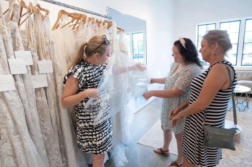 La novia Kimberly “Kiki” Waldrop, de Atmore, Alabama, eligiendo vestidos con su madre Rhonda Barrow, a la izquierda, y su abuela Kathy Rolin en Bliss Bridal en Fairhope, Alabama, el jueves 20 de junio de 2024.