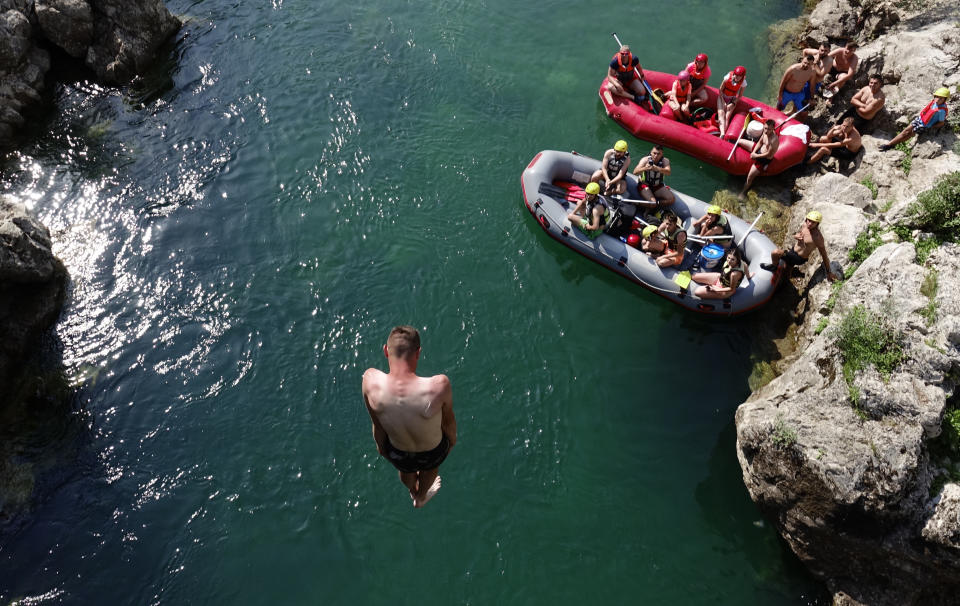A man jumps in the river of Neretva near the town of Konjic, Bosnia, Saturday, July 2, 2022. It took a decade of court battles and street protests, but Balkan activists fighting to protect some of Europe's last wild rivers have scored an important conservation victory in Bosnia. A new electricity law, which passed Thursday, bans the further construction of small hydroelectric power plants in the larger of Bosnia's two independent entities. (AP Photo/Eldar Emric)