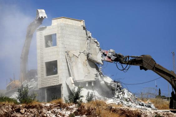 An Israeli army excavator machine demolishes a building in the Palestinian village of Sur Baher (EPA)