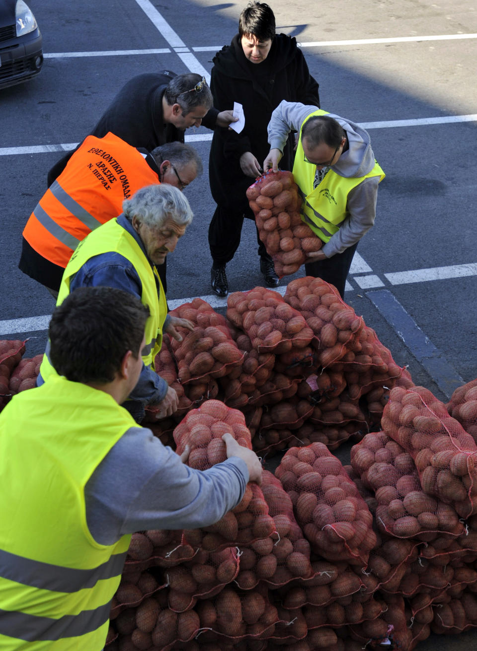 Farmers arrange sacks of potatoes for sale at cost price in the northern Greek town of Katerini, Greece on Saturday, Feb. 25 2012. Farmers in northern Greece have joined forces with local residents to provide cheap produce to people whose family budgets have been slashed by the financial crisis, and also to help producers who say they are being squeezed by middlemen. Hundreds of families turned up Saturday in this northern Greek town to buy potatoes at massively reduced prices, sold directly by producers at cost price. (AP Photo/Nicolas Giakoumidis)