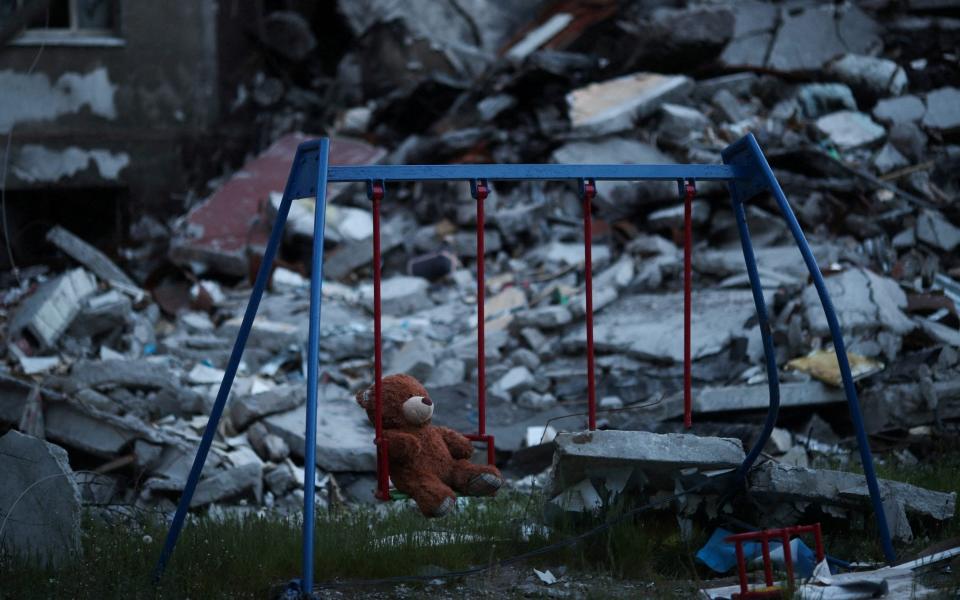 A teddy bear hangs on a swing next to a damaged building in Saltivka district, in Kharkiv - REUTERS/Ricardo Moraes