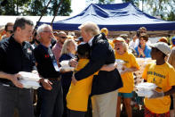 U.S. President Donald Trump embraces a boy while helping hand out meals with North Carolina Governor Roy Cooper (L) at a distribution center at Temple Baptist Church while participating in a tour of Hurricane Florence recovery efforts in New Bern, North Carolina, U.S., September 19, 2018. REUTERS/Kevin Lamarque