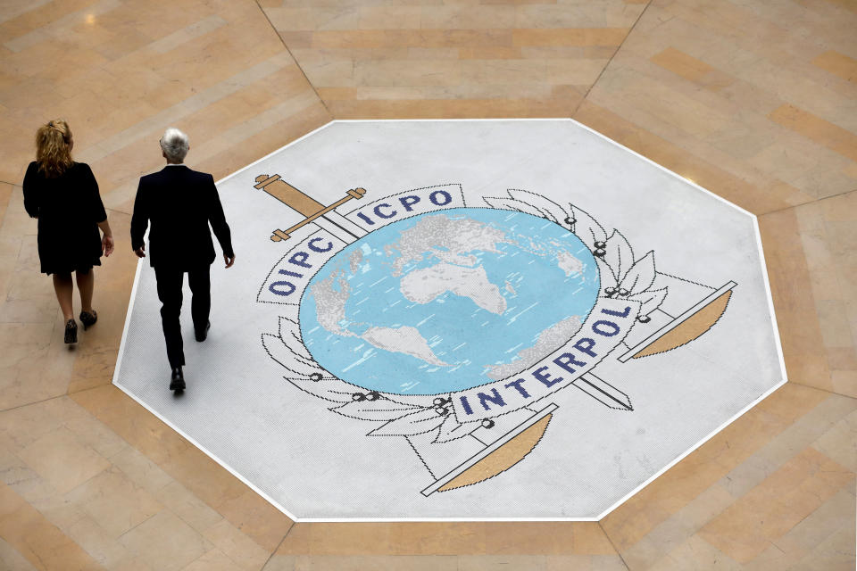 FILE - People walk on the Interpol logo at the international police agency headquarters in Lyon, central France, Nov. 8, 2018. Brazilian police official Valdecy Urquiza won a crucial vote of confidence Tuesday, June 25, 2024, toward becoming the next head of Interpol, the international police body, and its first non-Western chief after its executive committee selected him as its preferred candidate. (AP Photo/Laurent Cipriani, File)