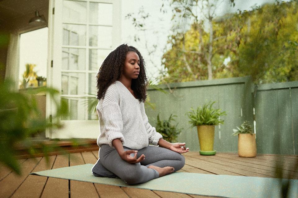 Young woman sitting in the lotus pose outside on her patio