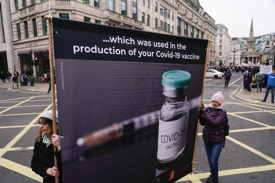 People hold placards as they attend an anti vaccines protest, in London, Saturday, Jan. 22, 2022.(AP Photo/Alberto Pezzali)