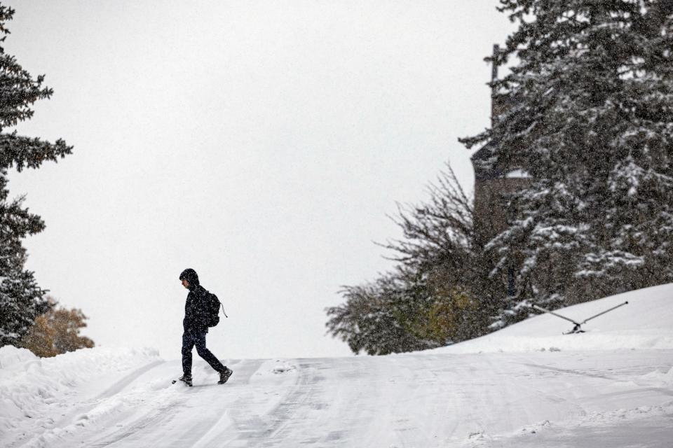 A pedestrian crosses a snow-covered road Wednesday in Helena, Mont. The first major snowstorm of the season dropped up to a foot of snow in the Helena area by te morning, canceling some school bus routes.