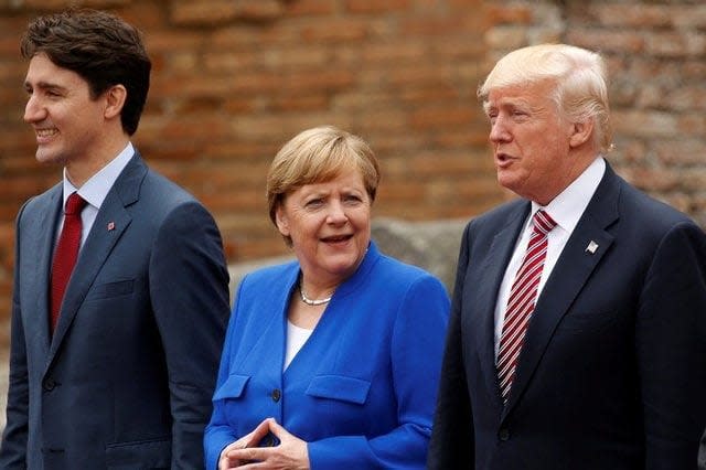 Mr Trump along with Angela Merkel and Justin Trudeau at the G7. Mr Trump has seen some of his steepest favourability ratings drops in his neighbours and the US's European allies  - Reuters