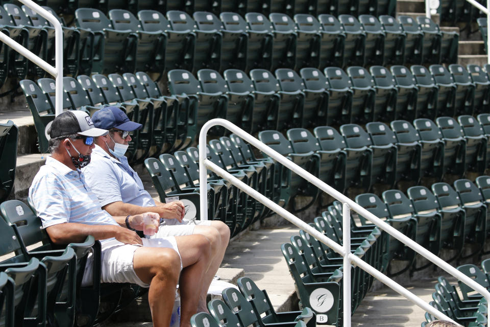 Tennis fans, Jeff Hartman, left, and Clay Gilbert, right, watch play at the start of the World Teamtennis tournament at an empty tennis arena at The Greenbrier Resort Sunday July 12, 2020, in White Sulphur Springs, W.Va. (AP Photo/Steve Helber)