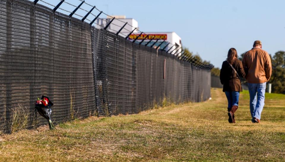 Flowers are left along the fence line of the airport (AP)