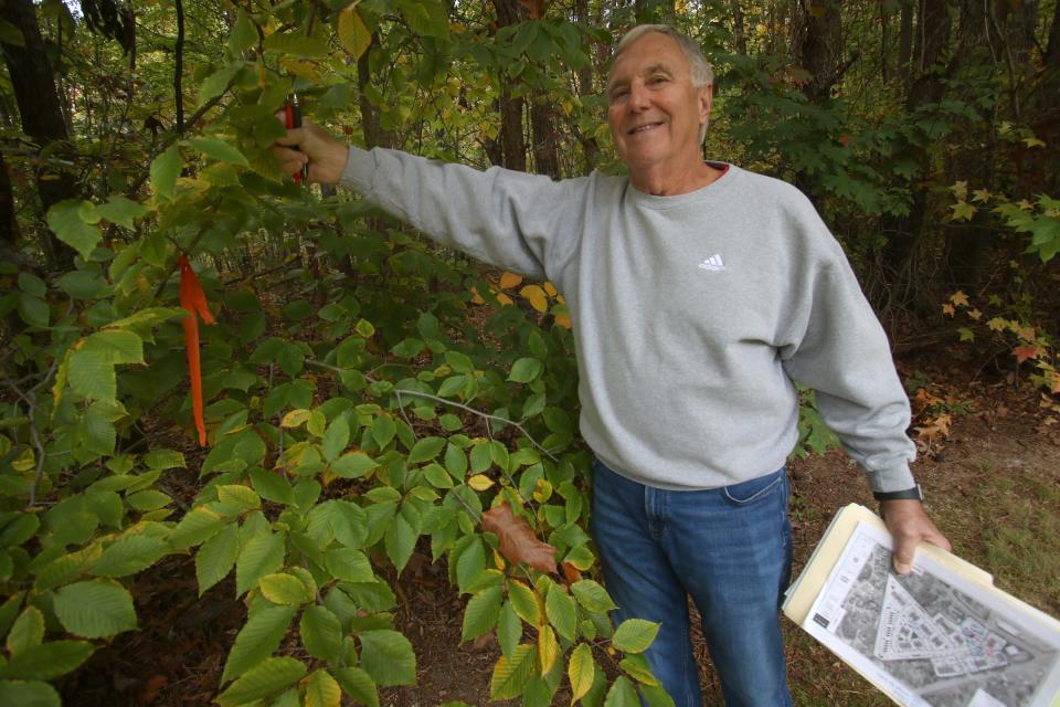 Bob Ferguson shows a property marker on the tree line near the back deck of Kate Hamad’s home on Candlewick Way near where apartments may be built.