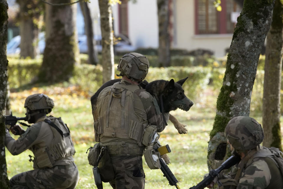 A soldiers holds a dog during a training at the 132nd canine infantry regiment in Suippes, eastern France, Thursday, Oct. 20, 2022. The 132nd canine infantry regiment, largest military kennel in Europe, is training for 45 years all elite dogs of the French Army. From tracking down suspects in the 2015 Paris attacks to fighting extremists in Africa's Sahel region, dogs have helped French soldiers, police officers and other rescuers saving lives for more than a century. (AP Photo/Christophe Ena)