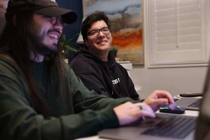 GARDENA-CA-MARCH 22, 2024: D'Angelo Ahumada, 18, center, sits with his mentor Matthew Pena, left, at home in Gardena on March 22, 2024. Disability rights groups and advocates have praised the Self-Determination Program, but complain that getting in can be demanding and take time - barriers that have led to underrepresentation of Latinos like Ahumada. (Christina House / Los Angeles Times)