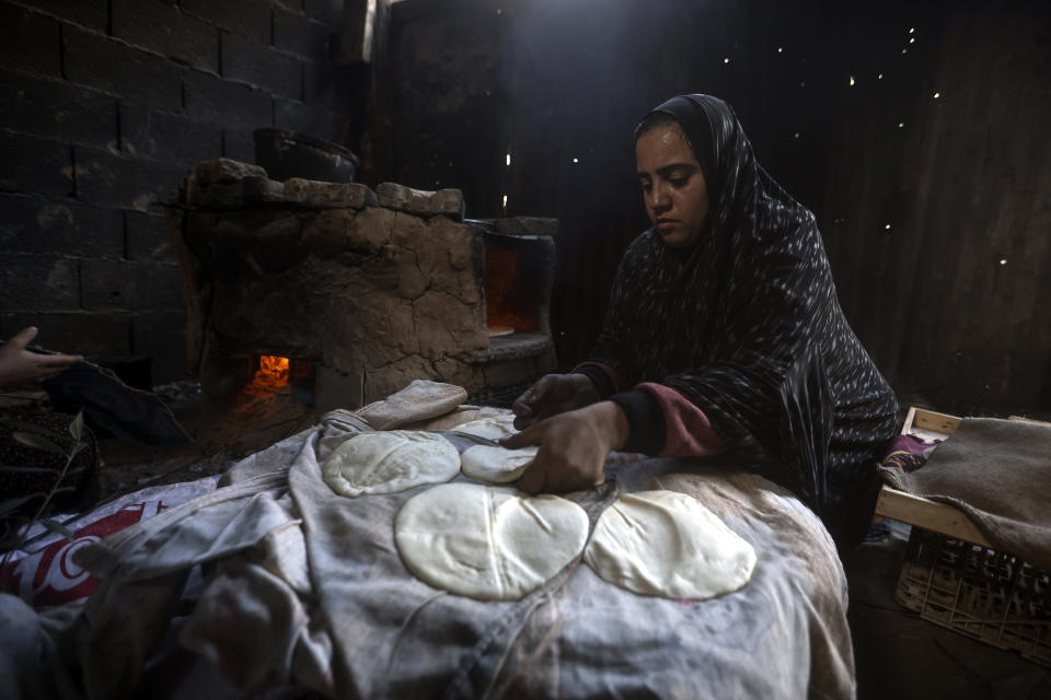 A Palestinian woman displaced by the Israeli ground offensive on the Gaza Strip bake bread at a makeshift tent camp in Rafah, Gaza Strip, Monday, Feb. 19, 2024. (AP Photo/Mohammed Dahman)