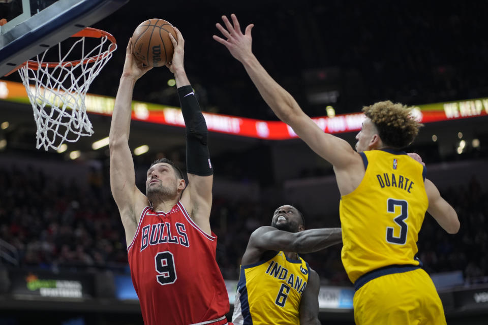 Chicago Bulls center Nikola Vucevic (9) shoots between Indiana Pacers defenders Lance Stephenson (6) and Chris Duarte (3) during the second half of an NBA basketball game in Indianapolis, Friday, Feb. 4, 2022. (AP Photo/AJ Mast)