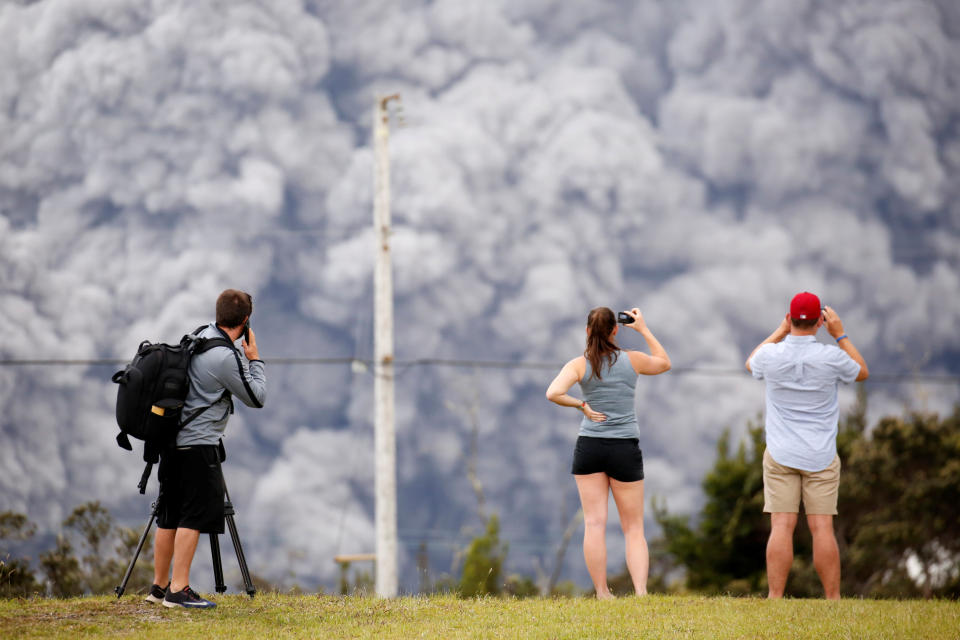 People watch as ash erupts from the Halemaumau Crater.