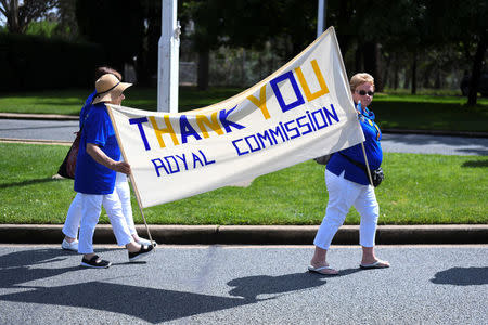 Members of the Care Leavers Australasia Network (CLAN) hold up a banner thanking the Commission as they await the final report from the Royal Commission into Institutional Responses to Child Sexual Abuse outside Government House in Canberra, Australia, December 15, 2017. AAP/Lukas Coch/via REUTERS