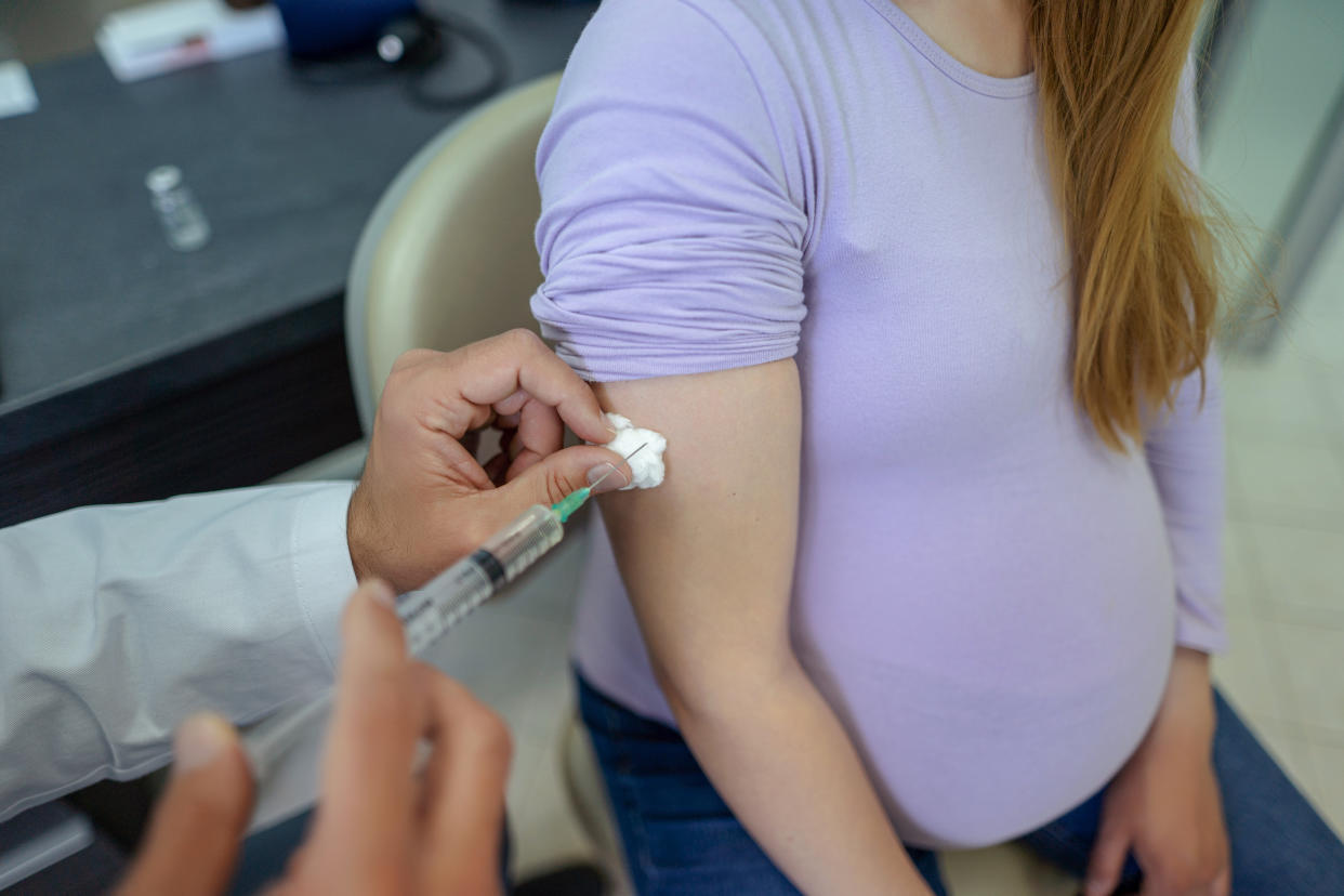 A pregnant young woman receives a vaccine at a preventive examination by a doctor