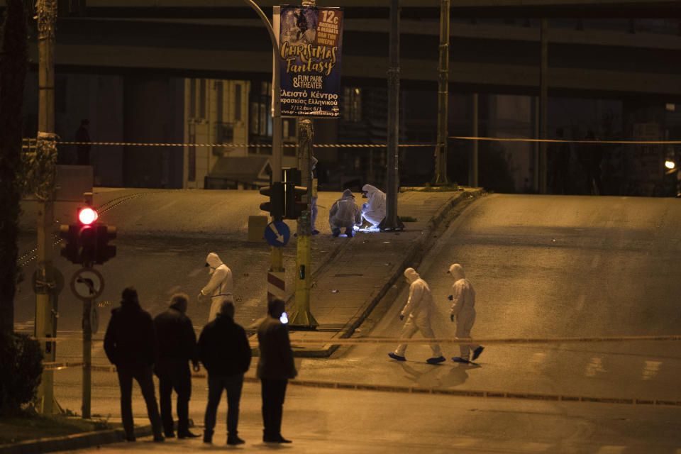 Greek forensic experts search at the scene after a powerful bomb exploded outside private Greek television station, in Faliro, Athens, Monday, Dec, 17, 2018. Police said the blast occurred outside the broadcasters' headquarters near Athens after telephoned warnings prompted authorities to evacuate the building, causing extensive damage but no injuries. (AP Photo/Petros Giannakouris)