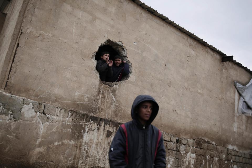 Children displaced by fighting in Mosul watch a visit by United Nations officials at a camp east of Mosul, Iraq, Wednesday, Feb. 15, 2017. The United Nations says they are temporarily pausing aid operations to neighborhoods in eastern Mosul retaken from the Islamic State group for security reasons as IS insurgent and counter attacks continue to inflict heavy civilian casualties there.(AP Photo/Bram Janssen)