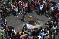 FILE - In this Oct. 17, 2019, file photo, a man waves an article of clothing in the smoke from the fire of a voodoo ceremony intended to confer protection to the people, as protesters call for the resignation of President Jovenel Moïse in the Delmar area of Port-au-Prince, Haiti. From Honduras to Chile, popular frustration with anemic economic growth, entrenched corruption and gaping inequality is driving the region’s middle classes to rebel against incumbents of all ideological bents in what has been dubbed by some the Latin American Spring. (AP Photo/Rebecca Blackwell, File)