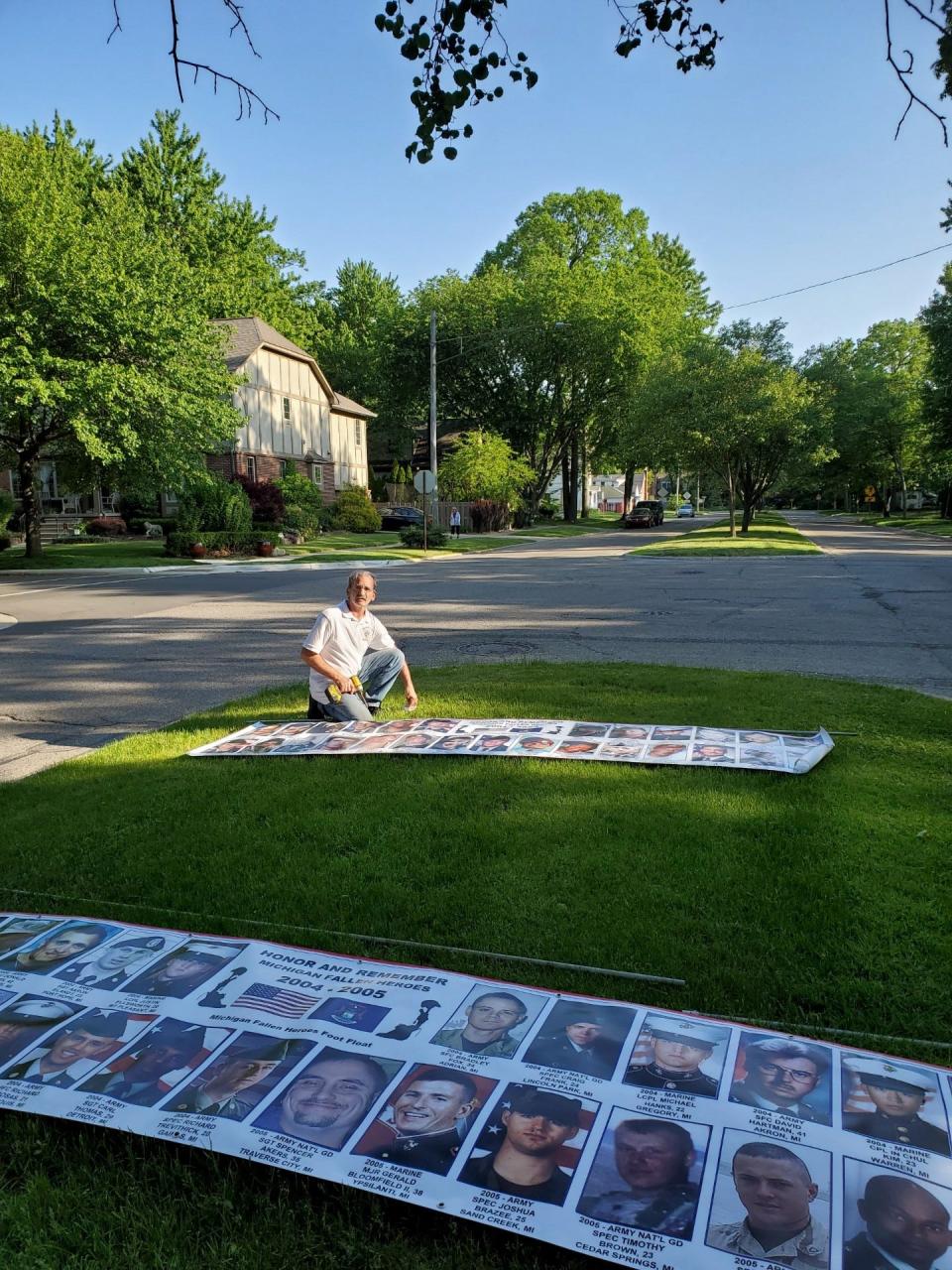 Chris Strzalkowski, a long time member of the Michigan Fallen Heroes Foot Float, sets out a memorial banner in 2023.