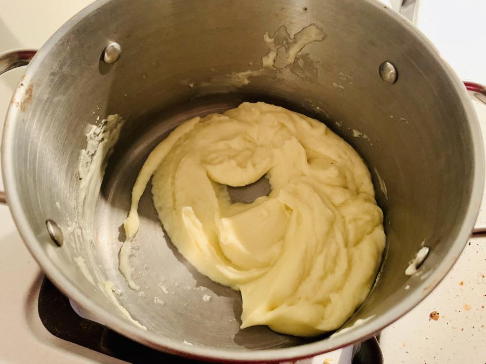 Warming Alinea mashed potatoes in silver pan on stove