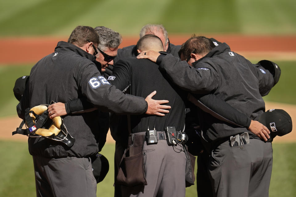 The umpires huddle at home plate before a wild card baseball playoff game between the Tampa Bay Rays and the Cleveland Guardians, Saturday, Oct. 8, 2022, in Cleveland. (AP Photo/Sue Ogrocki)