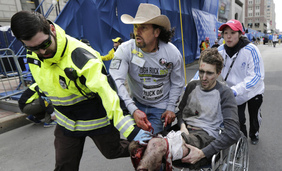 FILE - In this Monday, April 15, 2013, file photo, Boston EMT Paul Mitchell, left, bystander Carlos Arredondo, in cowboy hat, and Boston University student Devin Wang push Jeff Bauman in a wheelchair after he was injured in one of two explosions near the finish line of the Boston Marathon. Bauman and his three rescuers, became one of the most recognizable and powerful symbols of Boston's resilience after the April 15 attacks. (AP Photo/Charles Krupa)